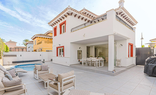 Image of a Mercia villa with white walls and dark orange accent colours around the windows and decorating the edge of the roof. There are beige chairs in the garden.